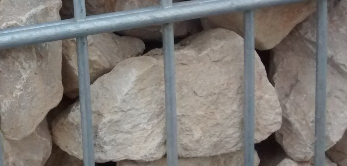 Beim Auffüllen der Gabione mit Bruchsteinen darauf achten, dass große Bruchsteine mit der glatten Fläche nach außen gelangen.